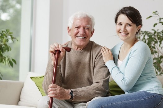 Smiling senior man with caregiver in living room