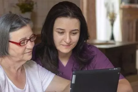 Staff assisting resident with a tablet