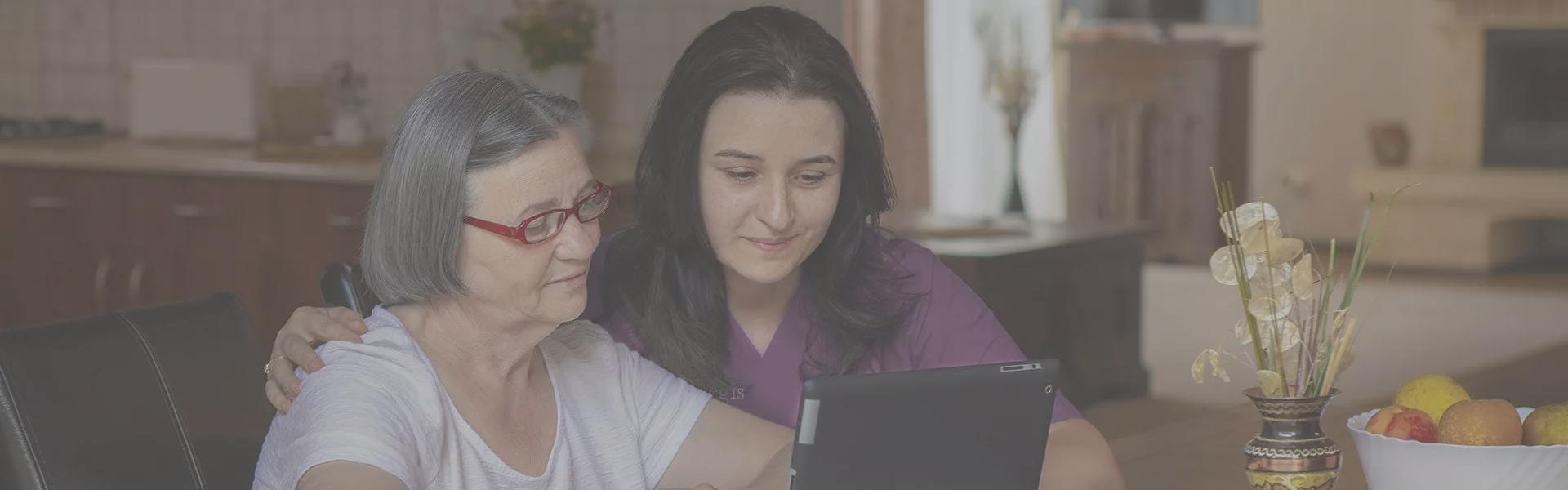 Staff member assisting a resident with a tablet.