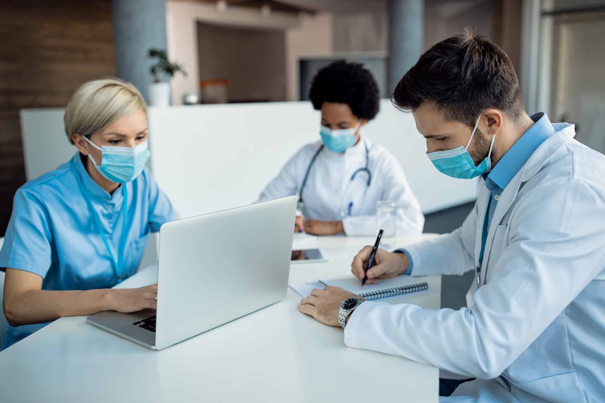 Healthcare staff collaborating over a laptop