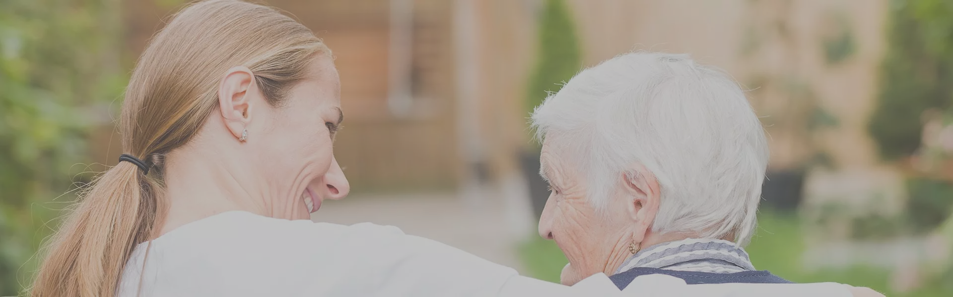 Caregiver and elderly resident enjoying a conversation outdoors.
