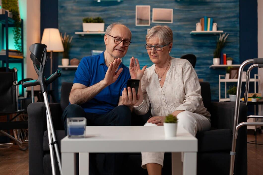 Two seniors engaged with a smartphone in a cozy living space.