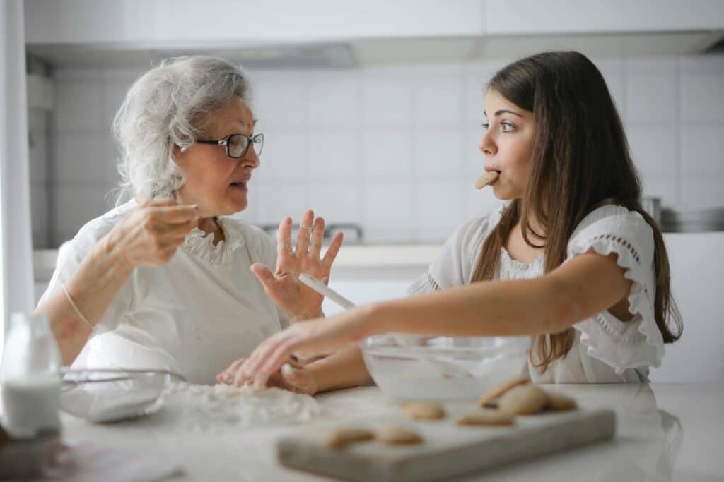 An elderly woman baking with a young girl.