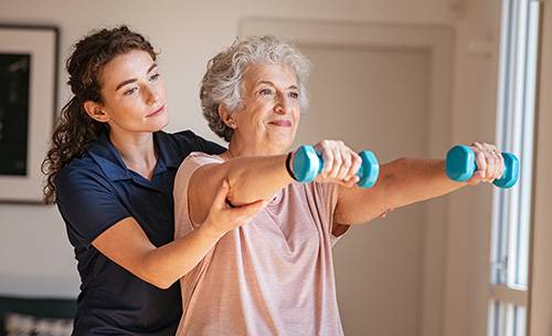 Senior exercising with the help of staff member.