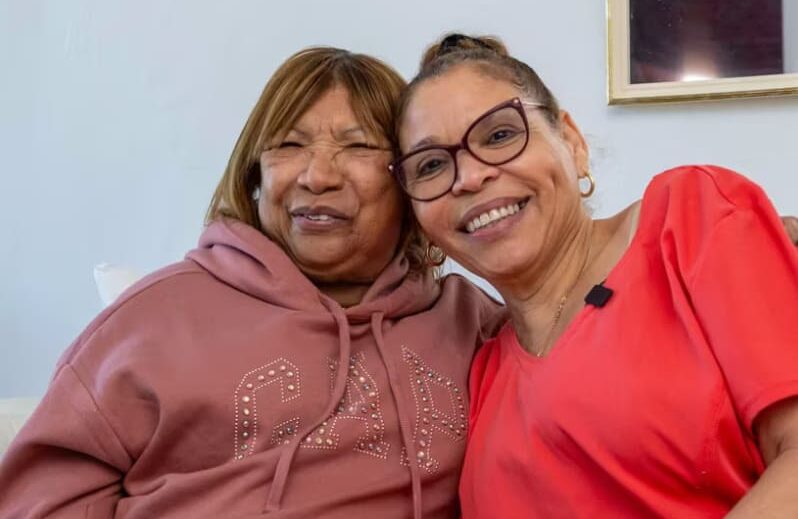 Two women smiling and posing together indoors.