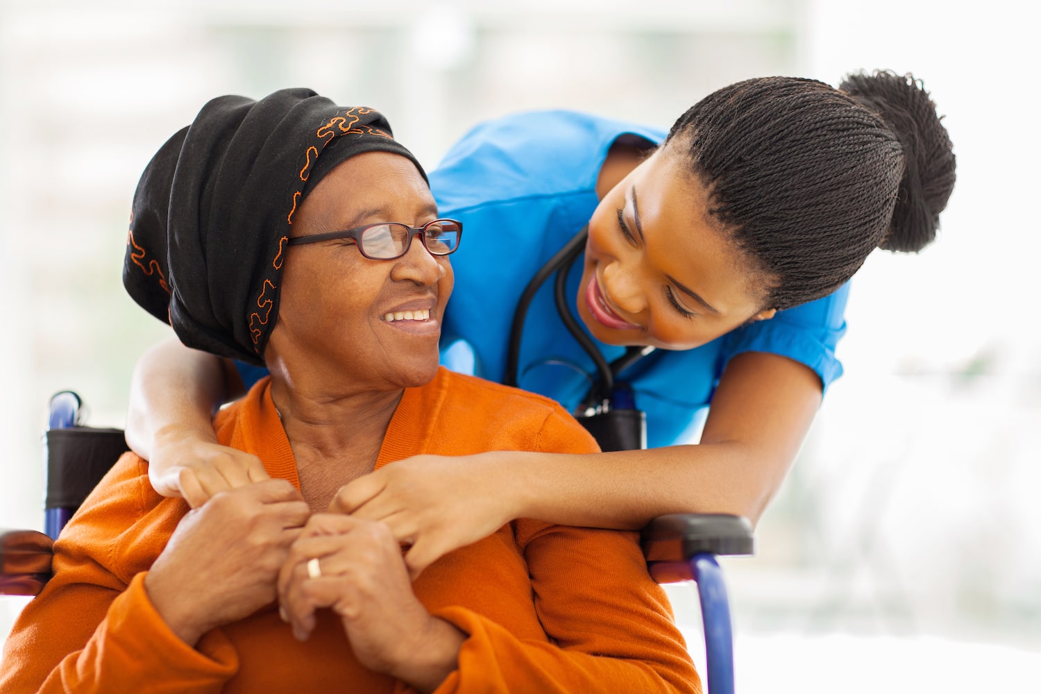 Resident and nurse smiling together in a care setting.