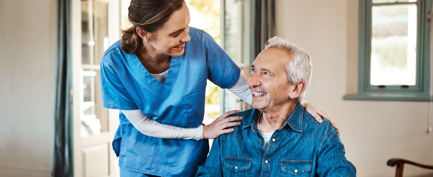 Caregiver smiling with an elderly resident in a cozy interior