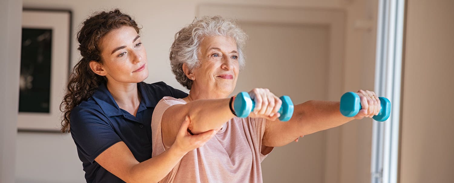 Caregiver assisting senior with light weights