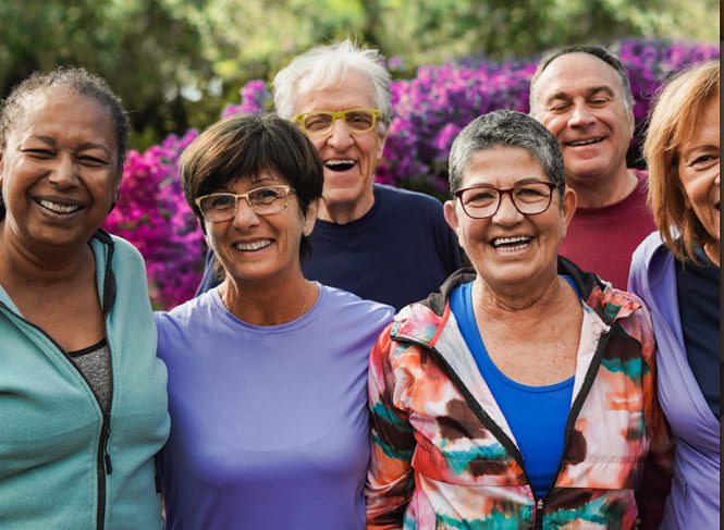 Group of seniors smiling outdoors with flowers