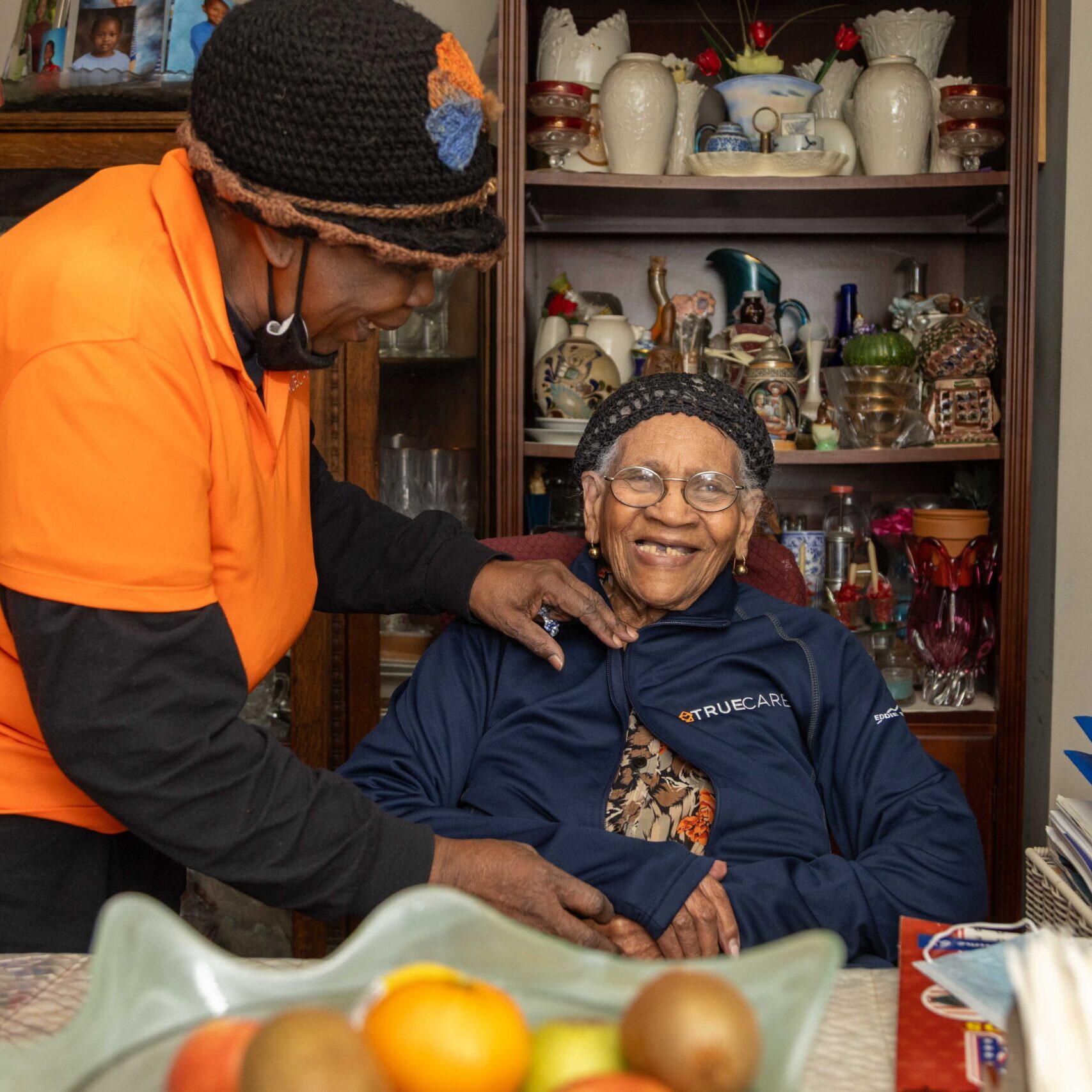 Caregiver assisting a smiling senior client indoors.