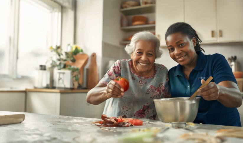 Resident cooking with staff in a kitchen