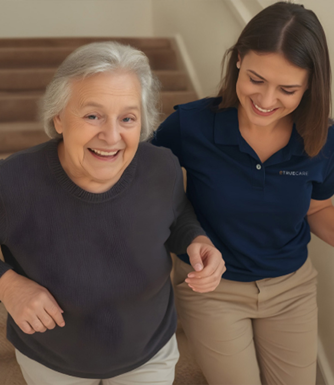 Senior resident and caregiver smiling on stairs