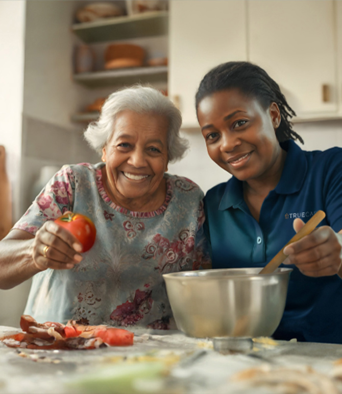 Resident cooking with staff member, cheerful atmosphere.