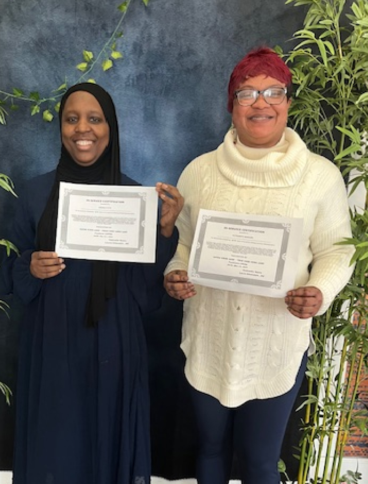 Two women holding certificates indoors.