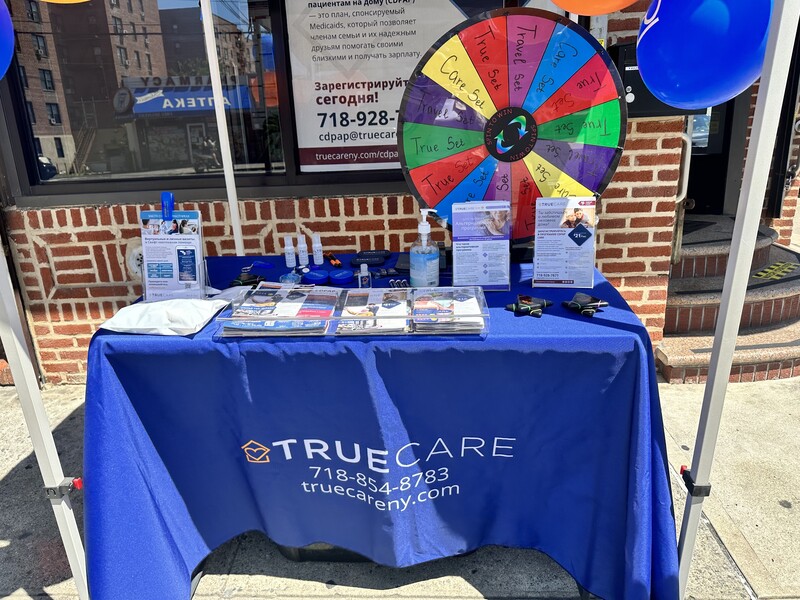 Outdoor promotional table with game wheel and brochures.