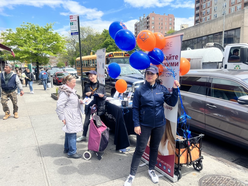 People engaging outside with balloons and information tables.