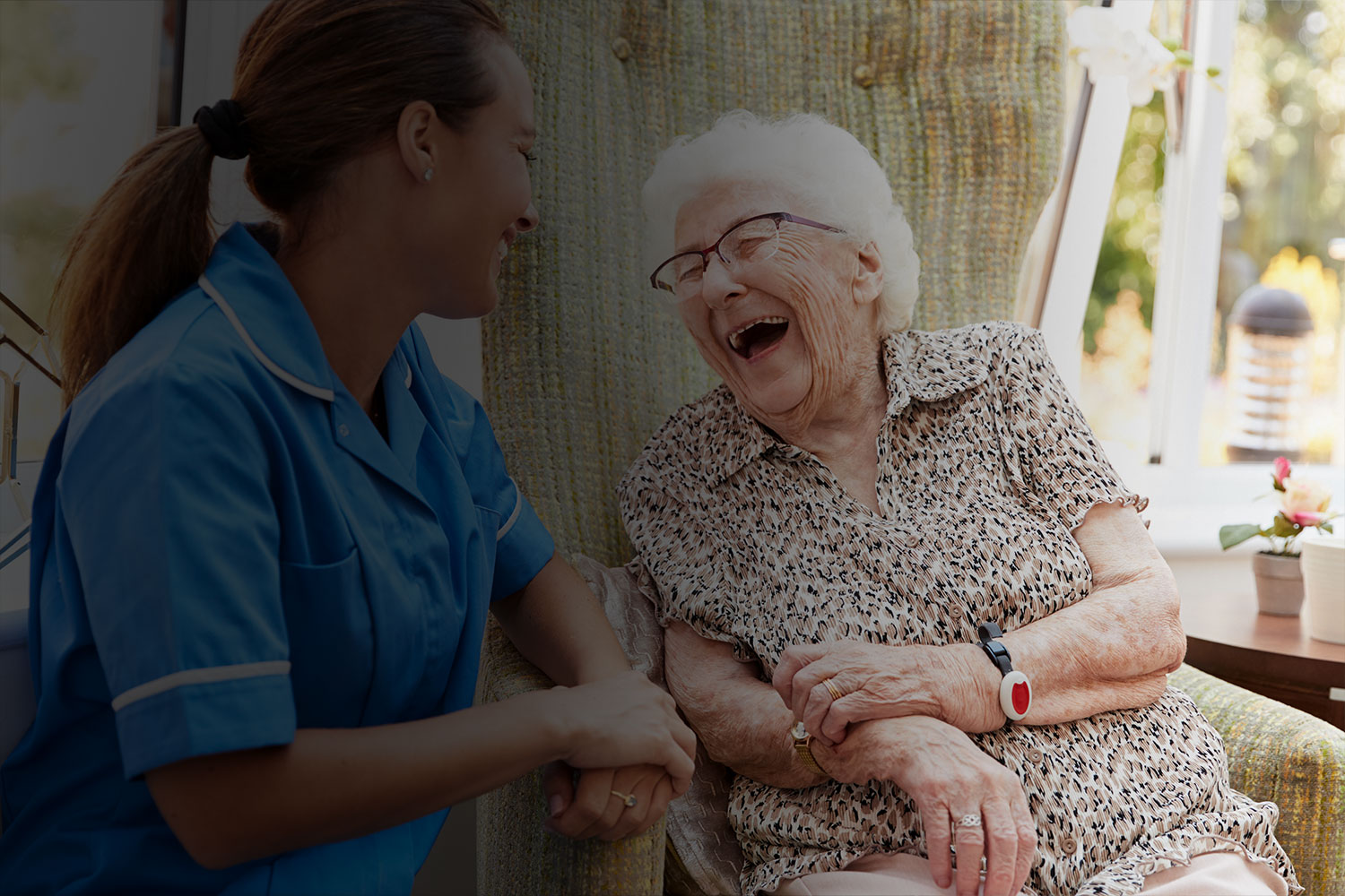 Caregiver and elderly woman sharing a joyful moment.