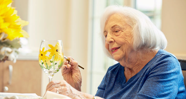 Senior woman painting a decorated glass.