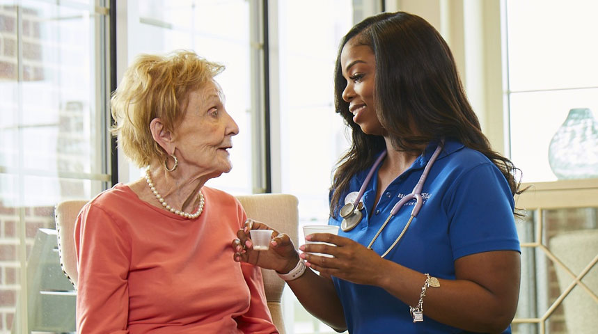 Nurse interacting with elderly resident in a cozy common area.