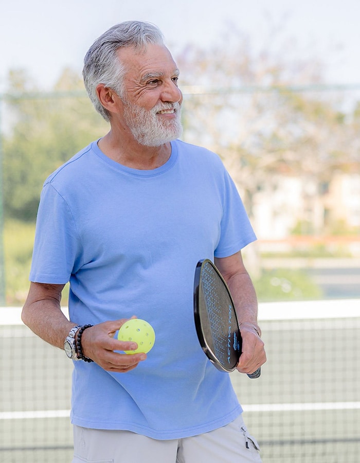 Senior man playing tennis outdoors.