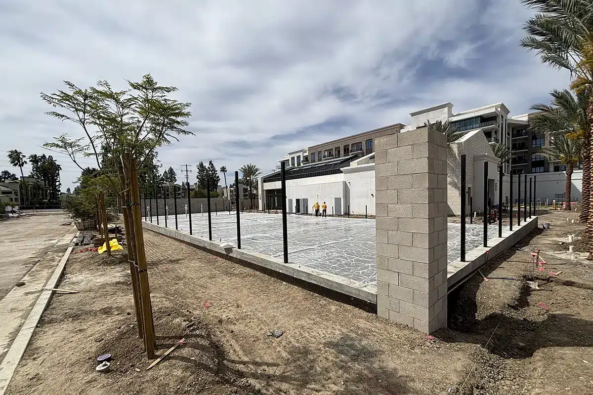 Construction site with newly poured concrete and fencing.