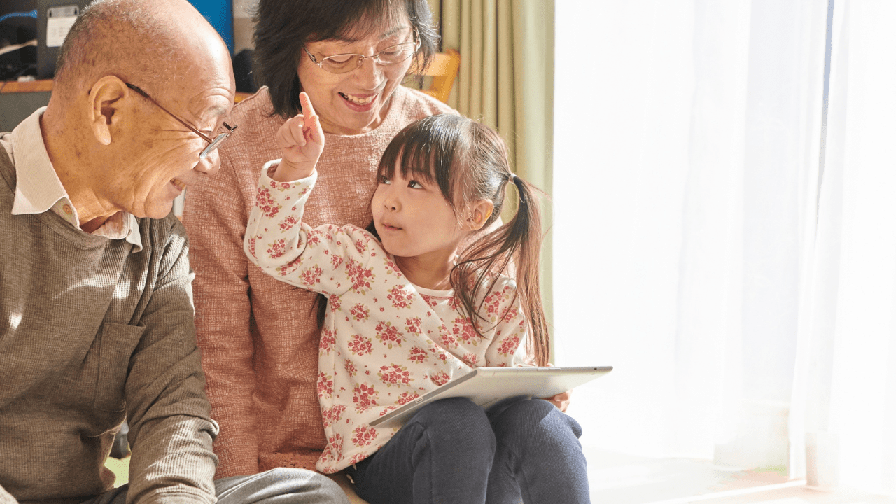Grandparents and granddaughter enjoying a tablet together.