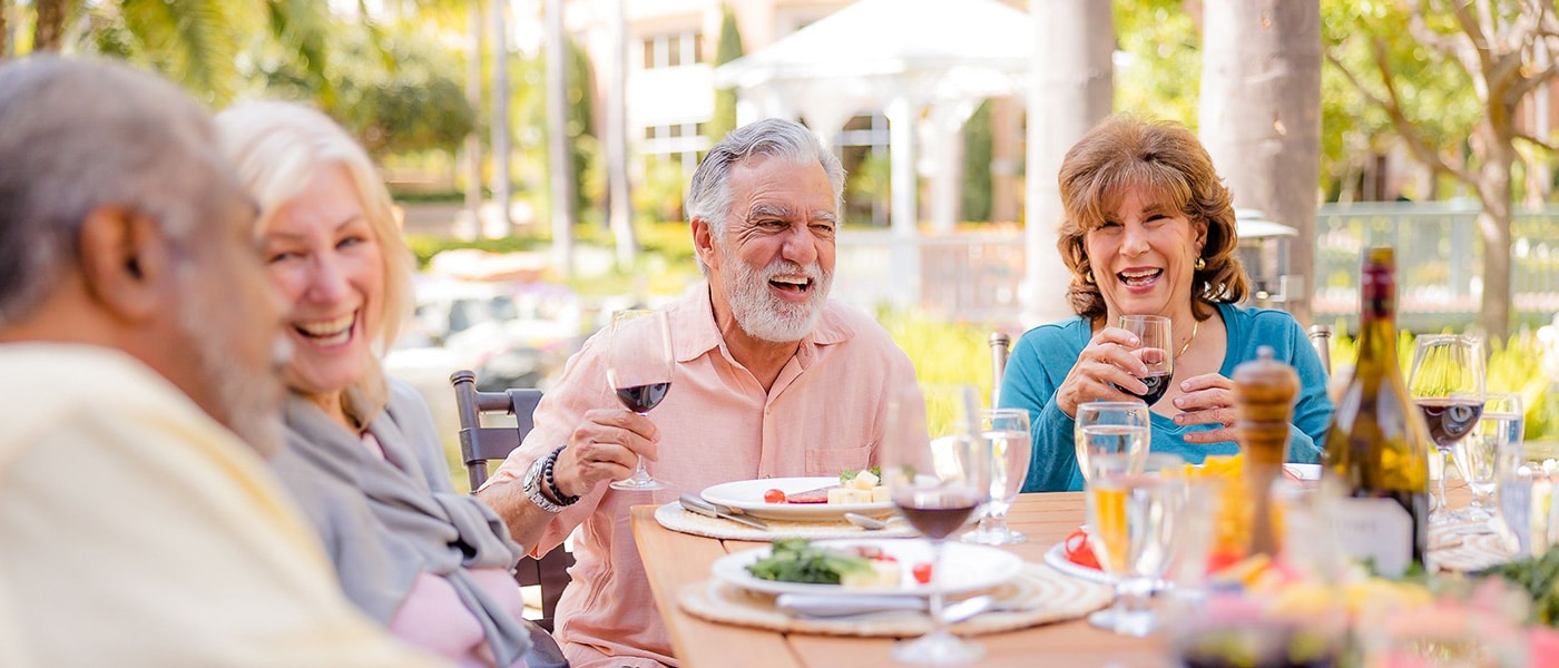 Seniors enjoying a meal outdoors with drinks