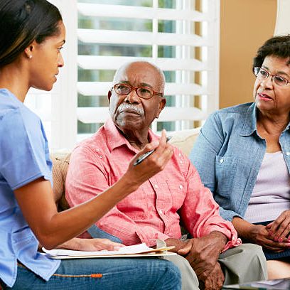 Caregiver discussing with senior residents indoors.