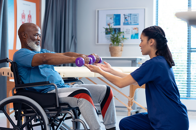 Therapist assisting senior man with weights