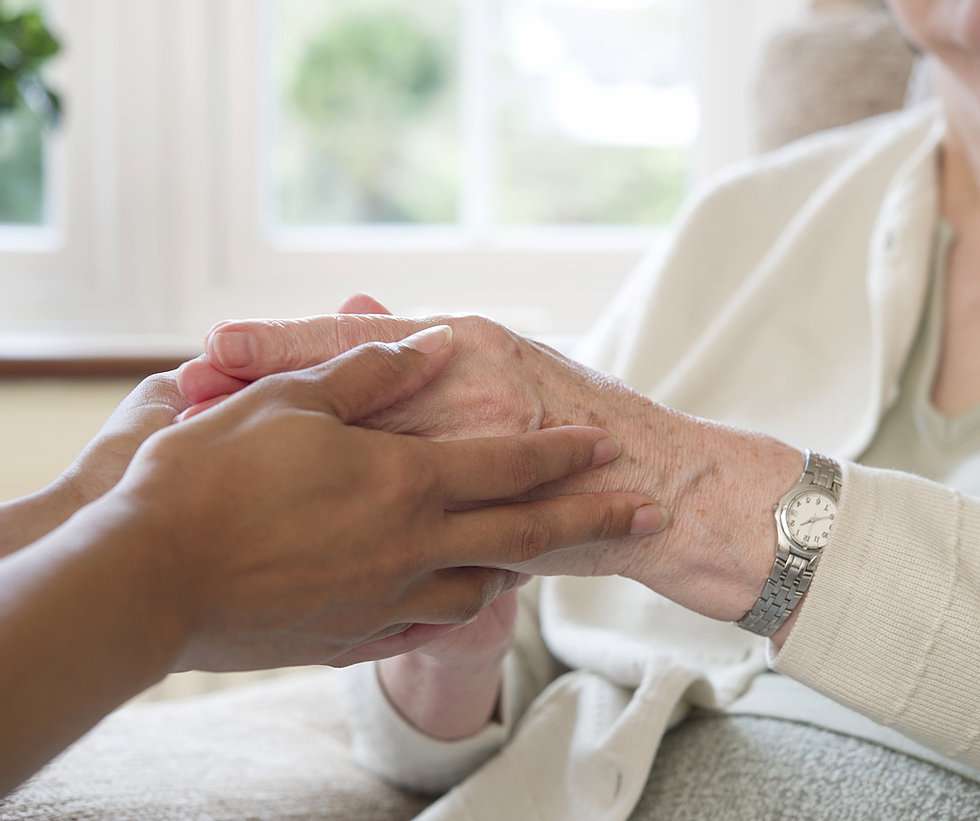 Caregiver holding the hand of a senior resident