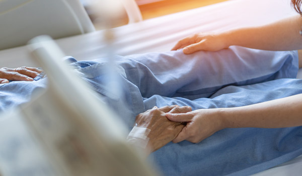 Caregiver gently holding patient's hand.