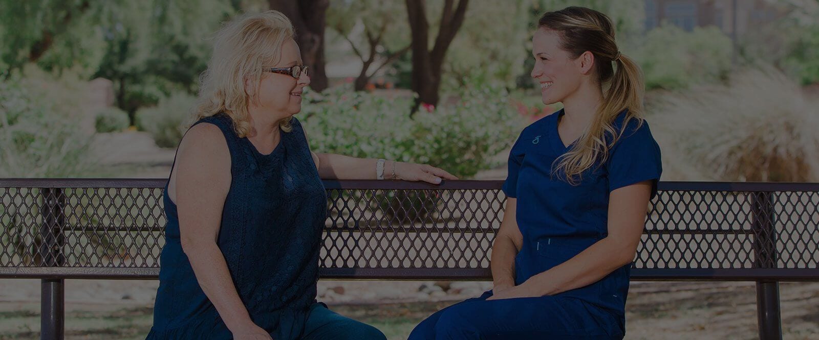 Caregiver chatting with a resident in a garden.