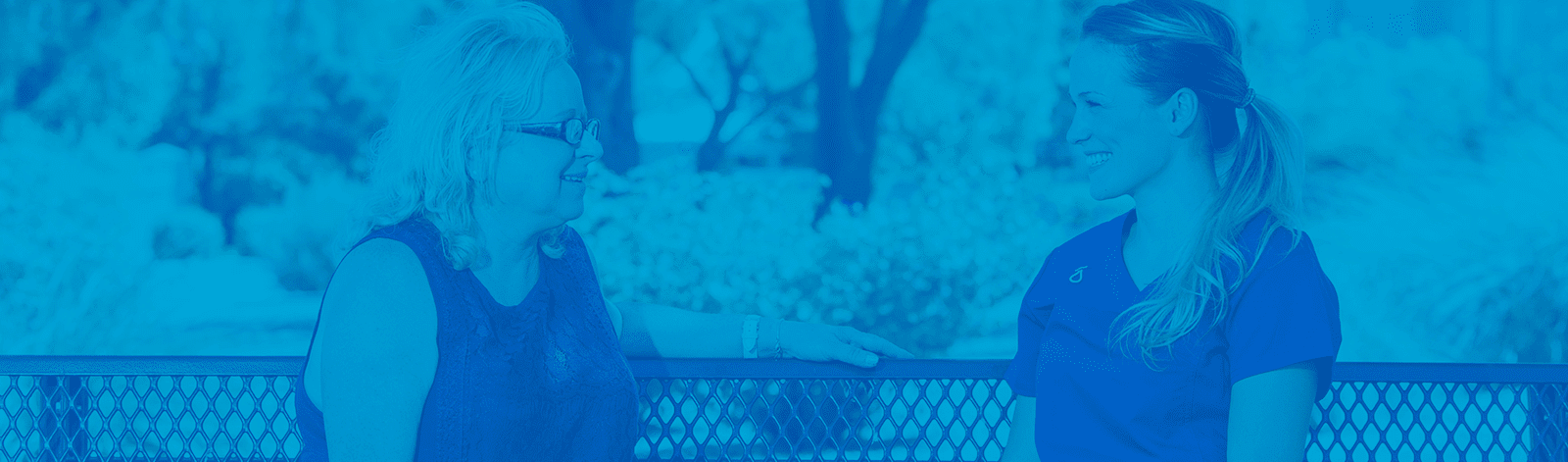 A caregiver and resident conversing outdoors.