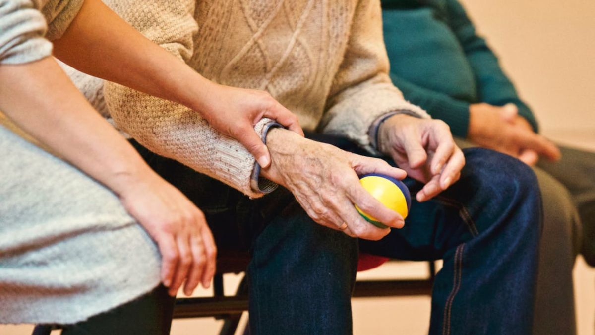 A caregiver holding an older adult's hand