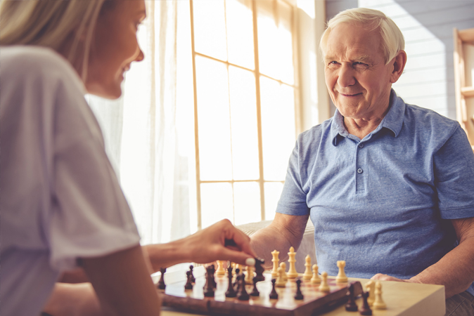 Senior man playing chess with a caregiver