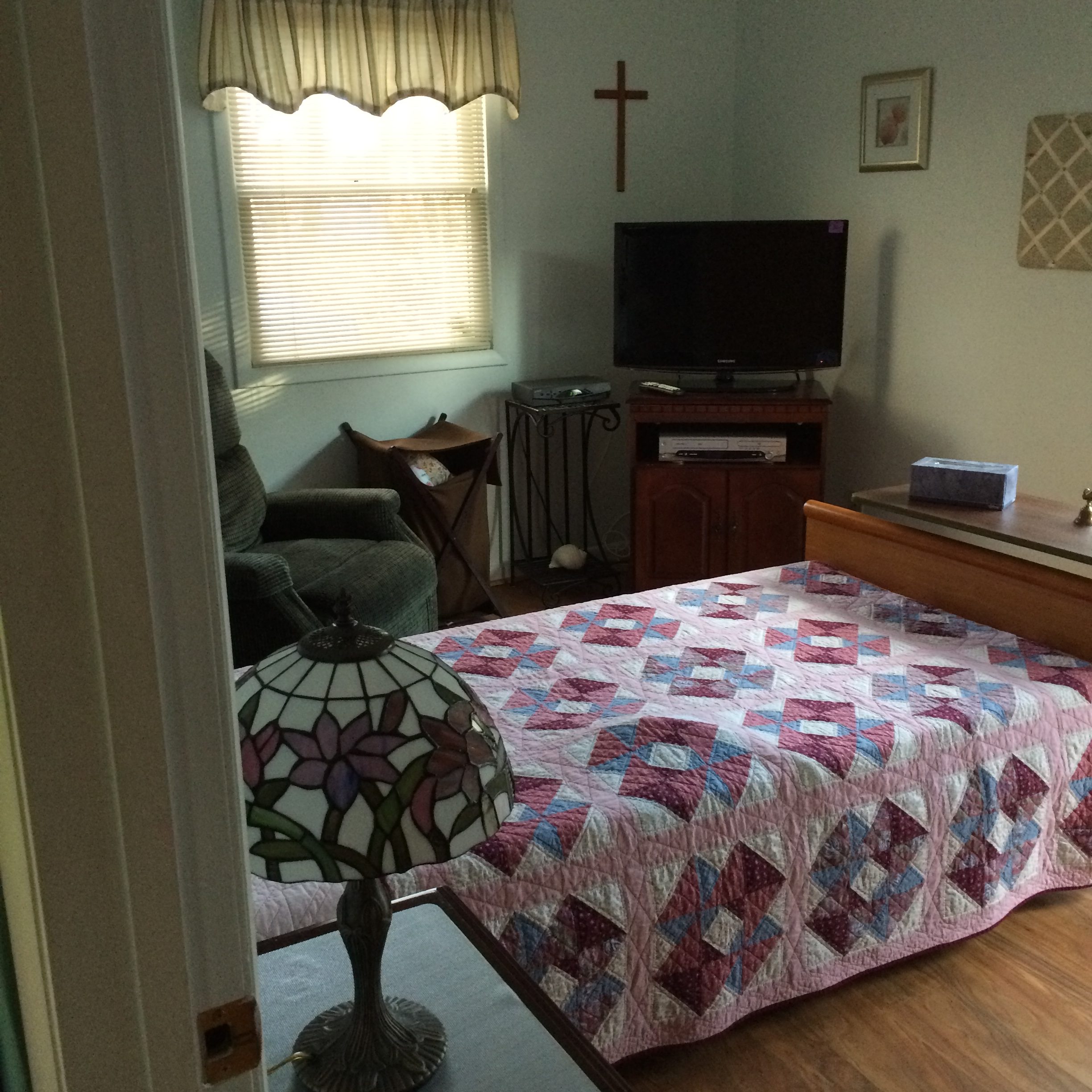 Cozy resident room with quilt and TV.