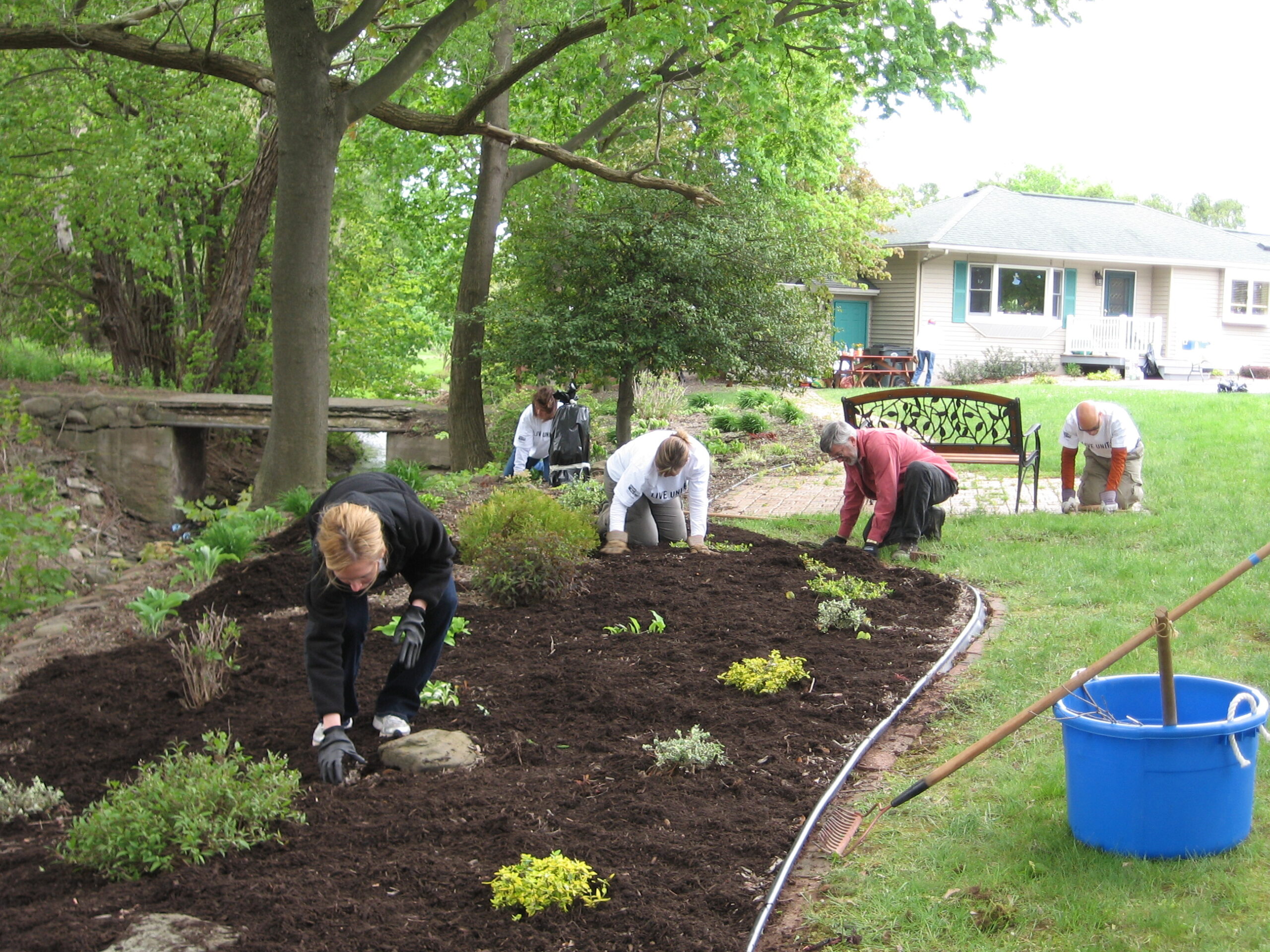 Residents gardening in a flower bed outdoors.
