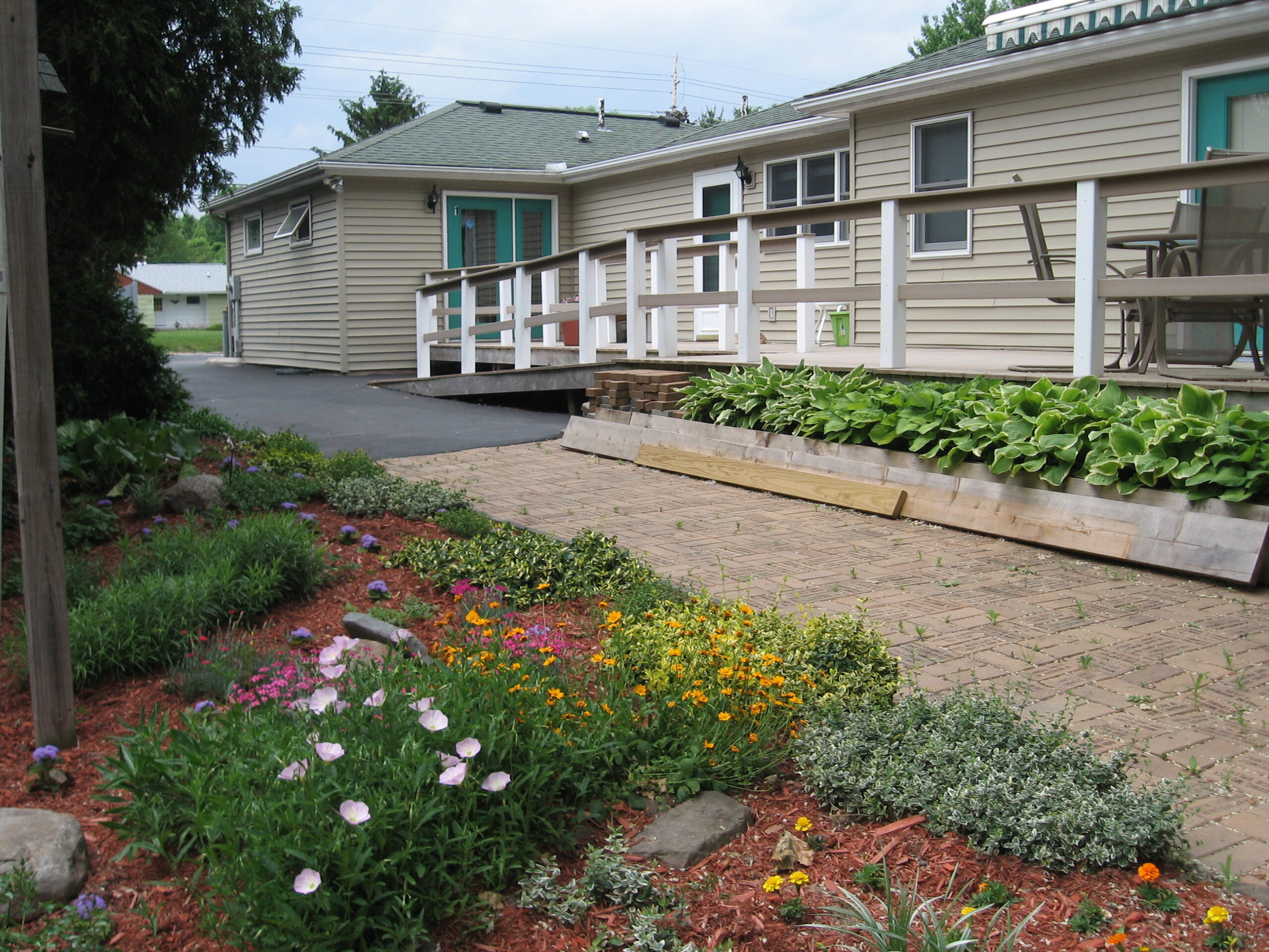 Pathway leading to a facility with flowering plants and green landscaping.