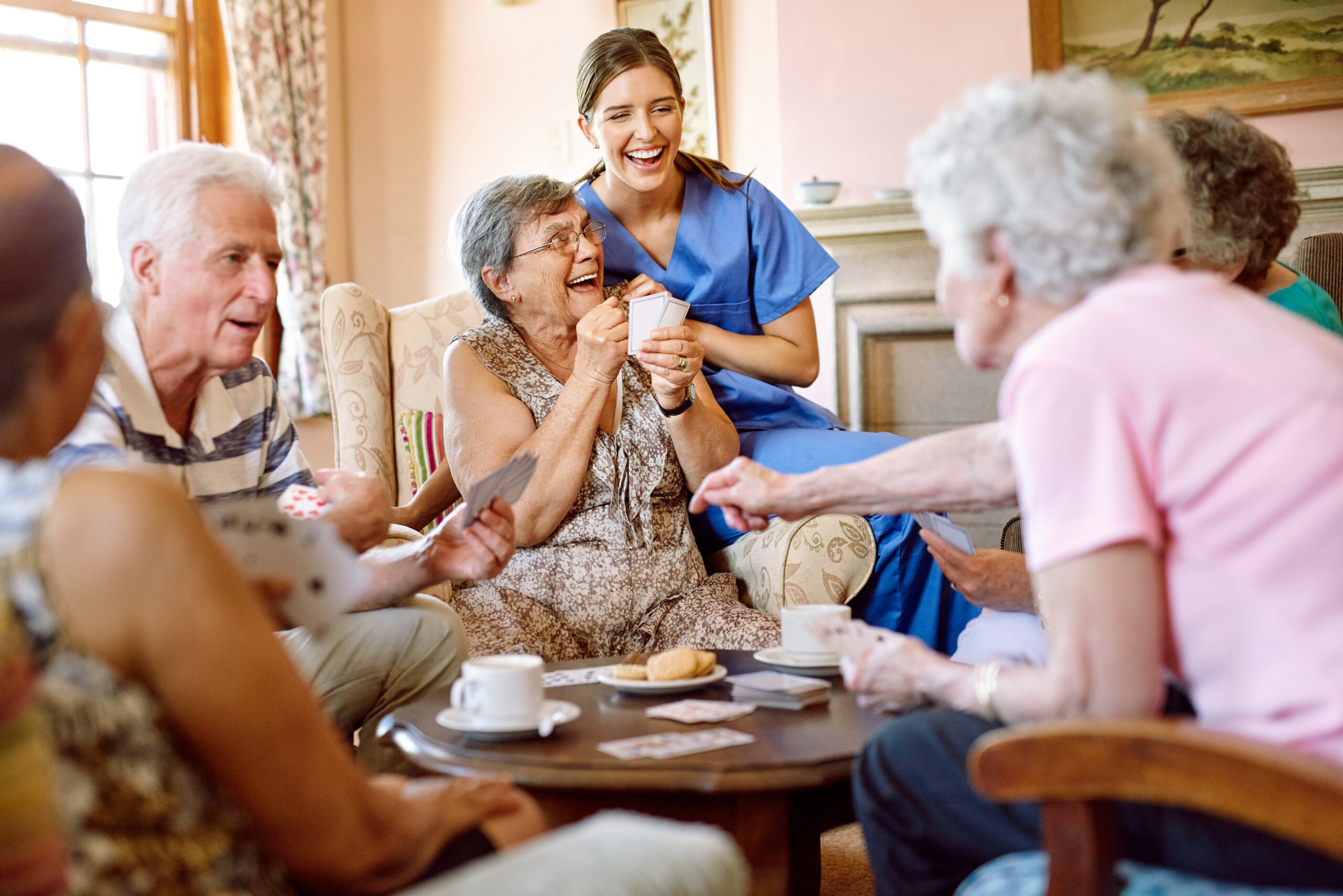 Residents enjoying a card game with staff in a common area
