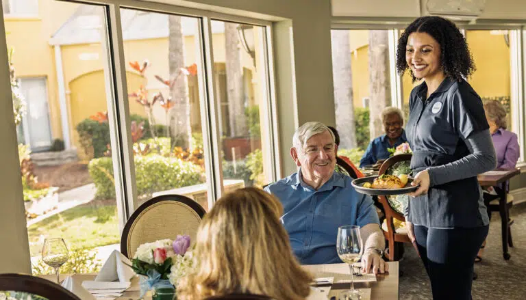 Resident receiving a meal from staff in dining area