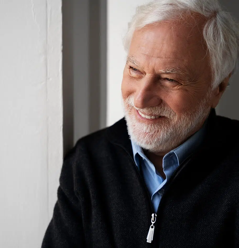 Smiling elderly man leaning by a wall