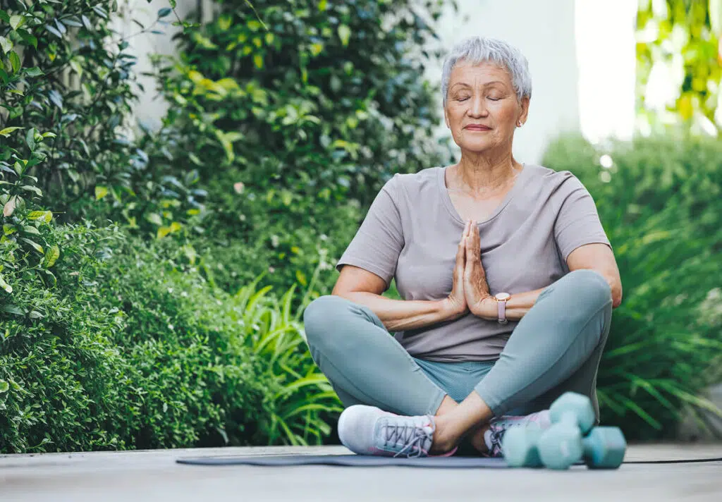 Senior woman meditating in a garden setting