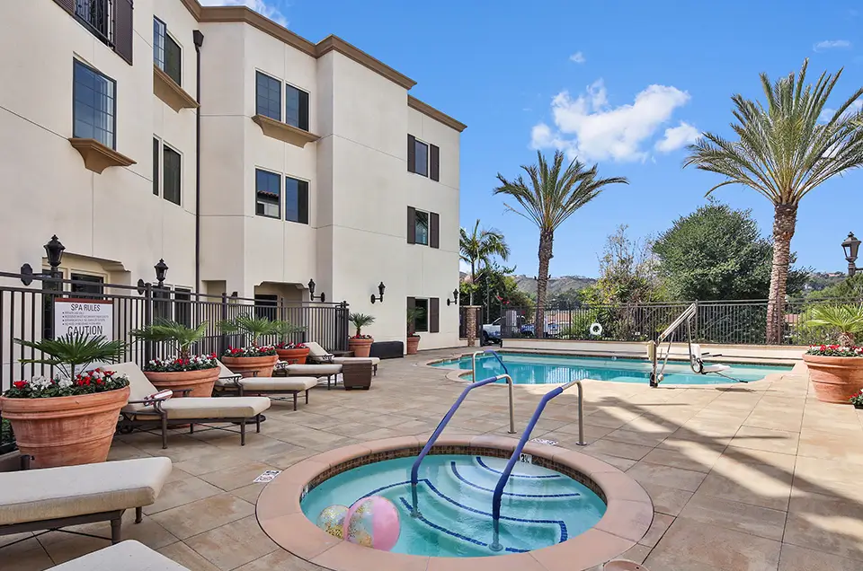 Outdoor pool area with lounge chairs and palm trees
