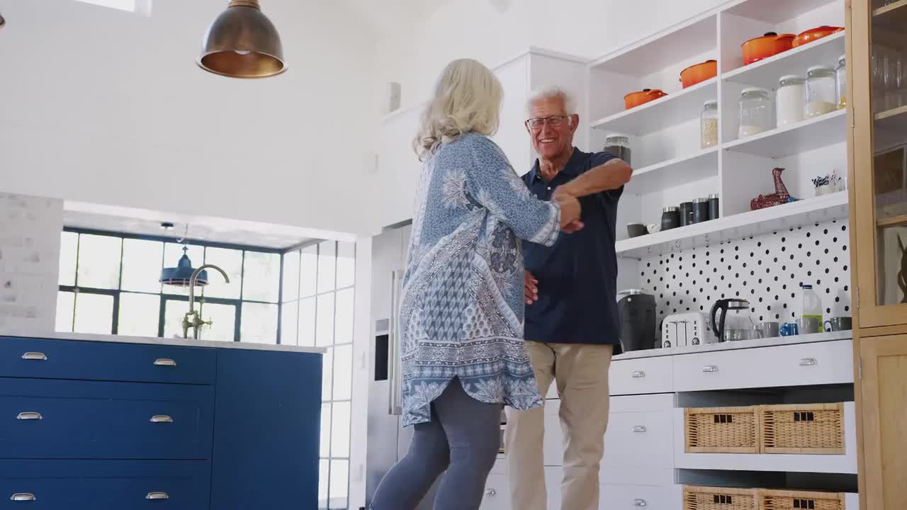 Seniors dancing joyfully in a modern kitchen