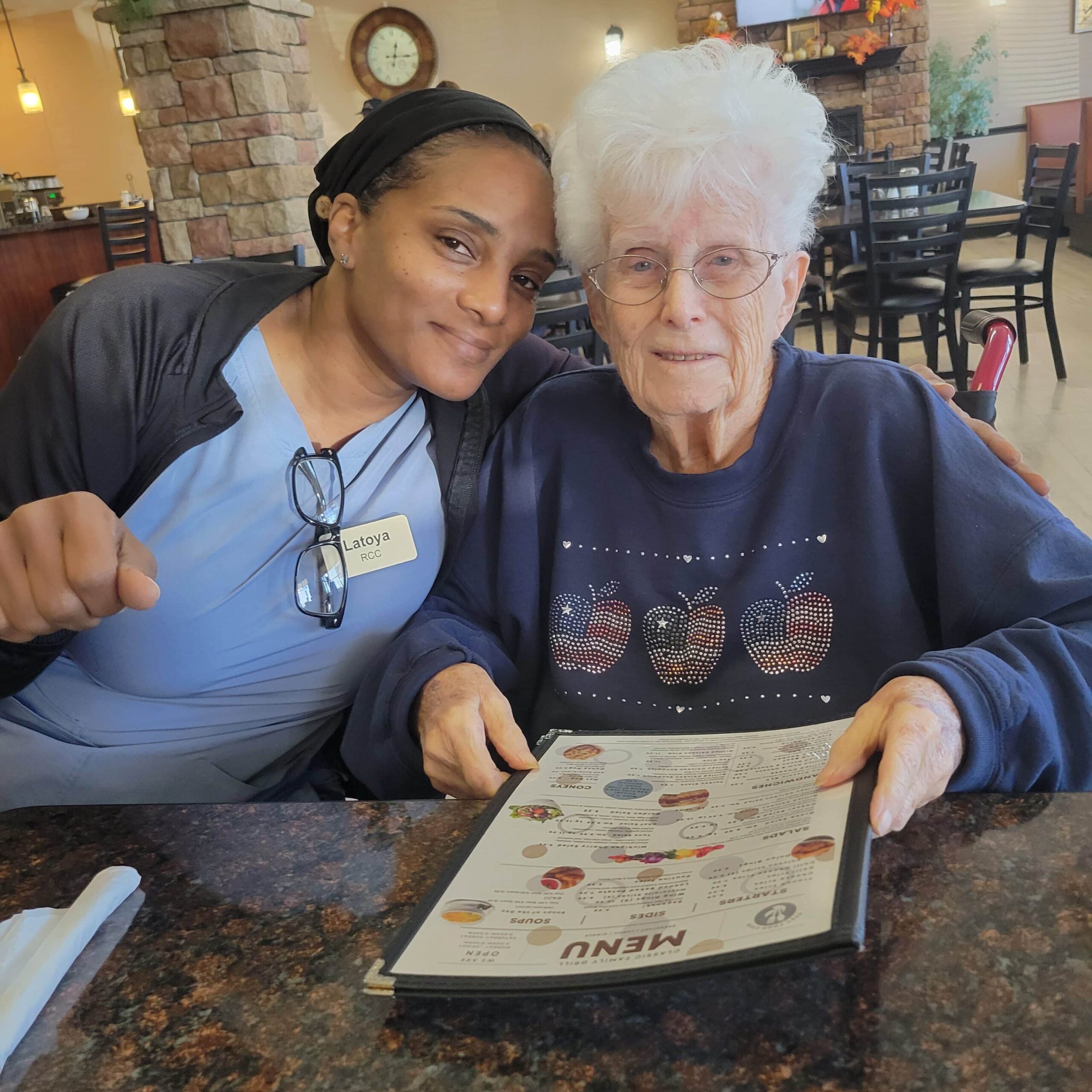 A caregiver and resident smiling in a common area