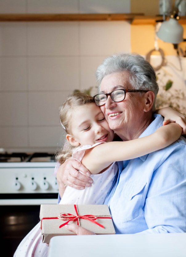 A senior woman hugging a young girl in a kitchen setting