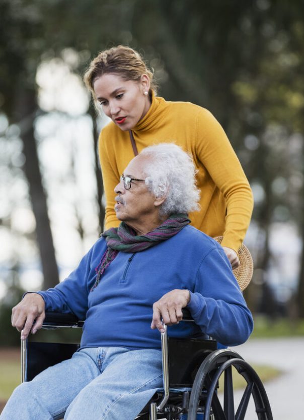 A caregiver assisting a resident in a wheelchair outdoors