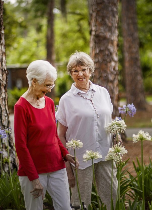 Two senior women enjoying a garden with flowers
