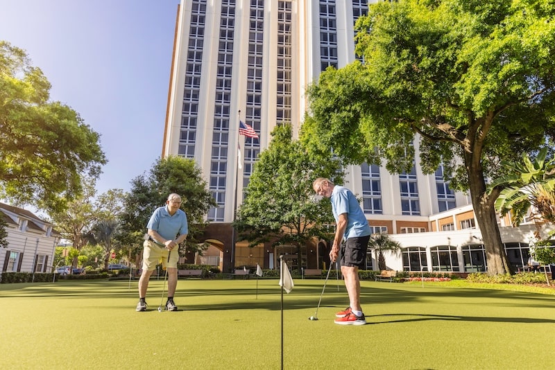 Residents playing golf on a putting green outside the facility