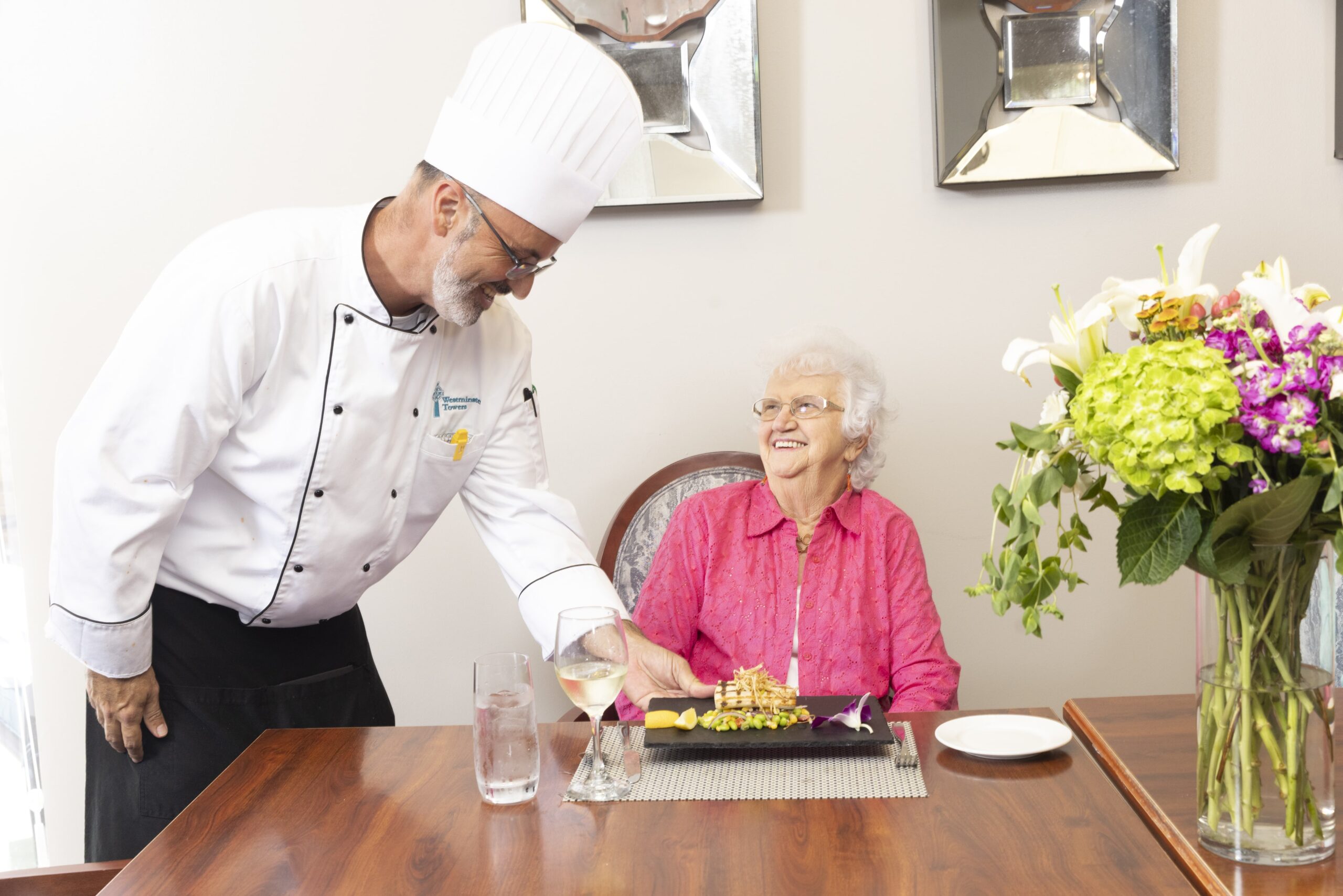 Chef serving a meal to a smiling resident